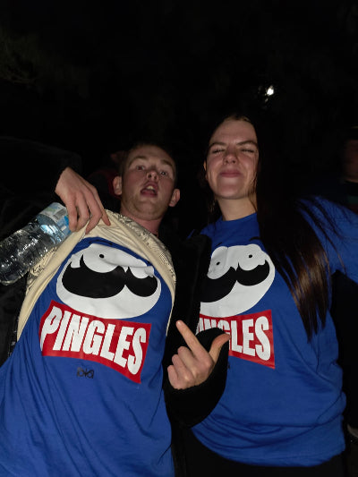 Two people wearing blue Nocturnal Notion 'Pingles' t-shirts at night.